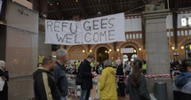 Banner Refugees Welcome is hanged by charity collecting point where locals bring clothes for refugees.