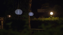 White Chinese lanterns hanging in dark house garden at night