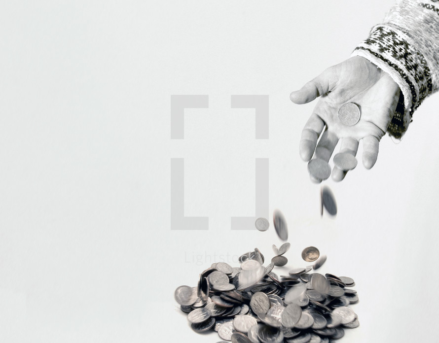 A person's hand throwing coins into a pile
