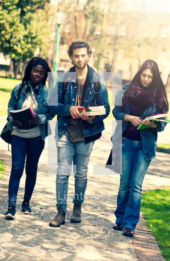 Multiracial group of students walking with books 