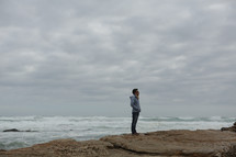 Man standing on cliff overlooking ocean