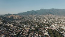 Beautiful high mountain peaks of the Southern Sierra Madre mountain area in Mexico with several neighborhoods of the large city of Oaxaca in Mexico in the foreground. Drone lowering tilt shot