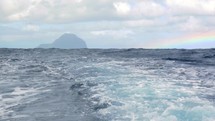 Wavy ocean and distant island, view from the ship