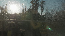 Looking outside through the wet glass. Condensation on the window in bright and sunny morning