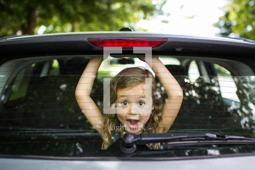 Little girl looking through back car window