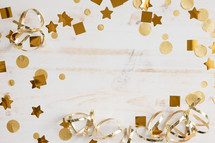 Gold confetti and streamers on a white wood background with copy space
