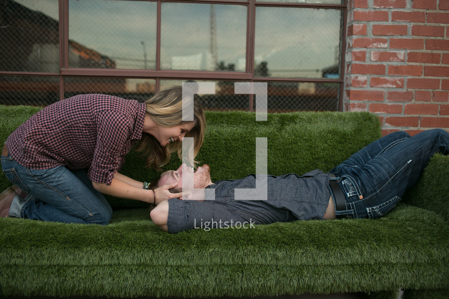 woman leaning over a man on a green fuzzy couch