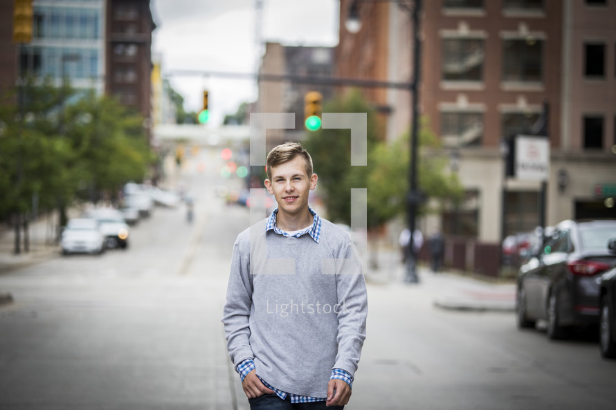 teen boy standing in the middle of a downtown street 