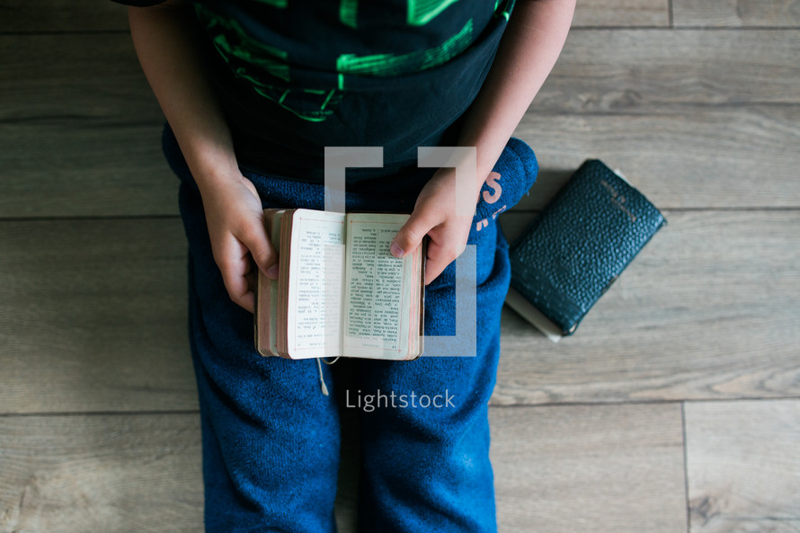 a boy reading from an old Bible 