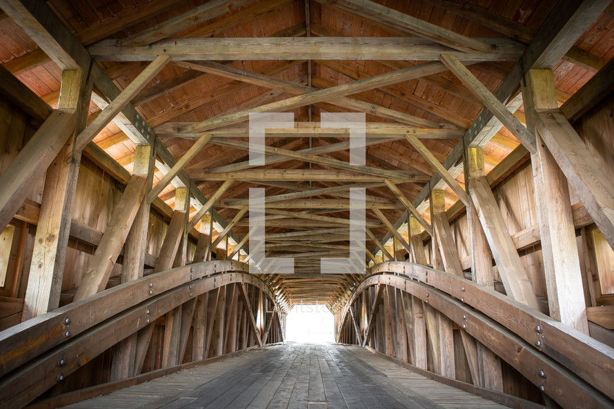 Wooden covered bridge leading to bright opening