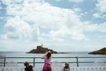 children looking over a railing towards a small island 