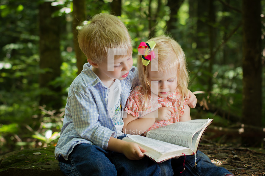 brother and sister reading a Bible together outdoors