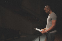 Man reading at a lectern on a stage.