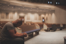 man alone  in prayer in an empty church