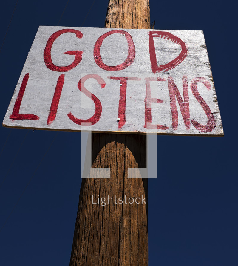"God Listens" sign nailed to a telephone post.