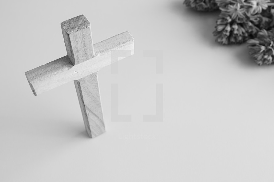 Black and white image of a wooden cross and flowers