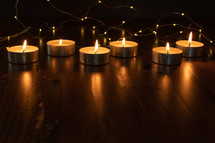 votive candles and string of fairy lights in darkness 