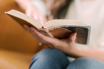 a woman reading a Bible with focus on her hand 