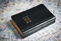 A Bible on top of one hundred dollar bills