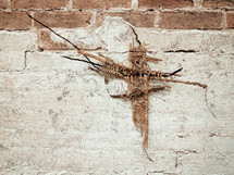 woven cross on a brick wall 