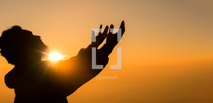 Silhouette of a man praying at sunset