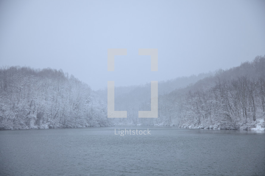 Foggy winter scene of snow covered trees on the edge of Dog Run Lake, West Virginia