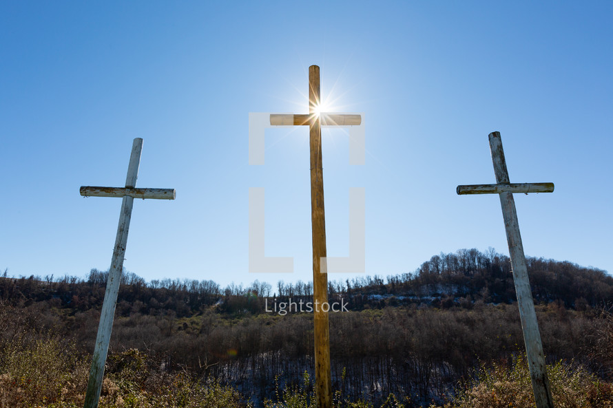 Sunlight on three wooden crosses on hill