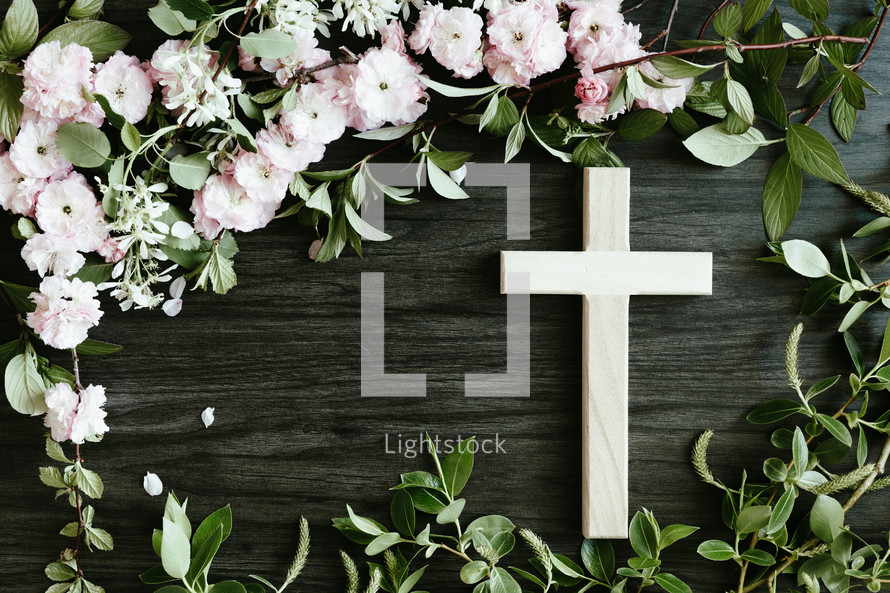 cross and pink flowers on black wood background 