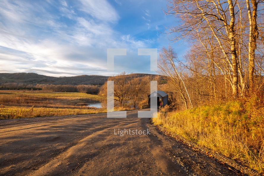 Path leading to covered footbridge during autumn panorama