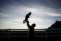 silhouette of a father tossing his toddler son in the air