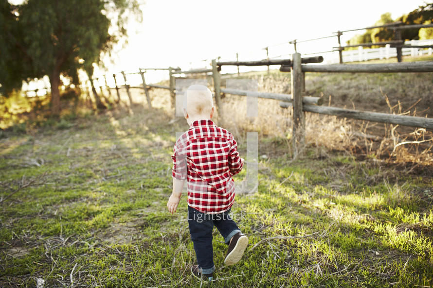toddler boy running in a pasture