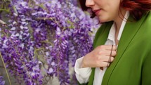 Woman standing next to wisteria praying the sign of the cross.