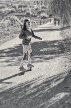 a child riding a skateboard on a path at a park 