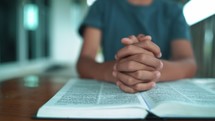 Close up hands of christian reading Bible and praying on at wooden table in morning.