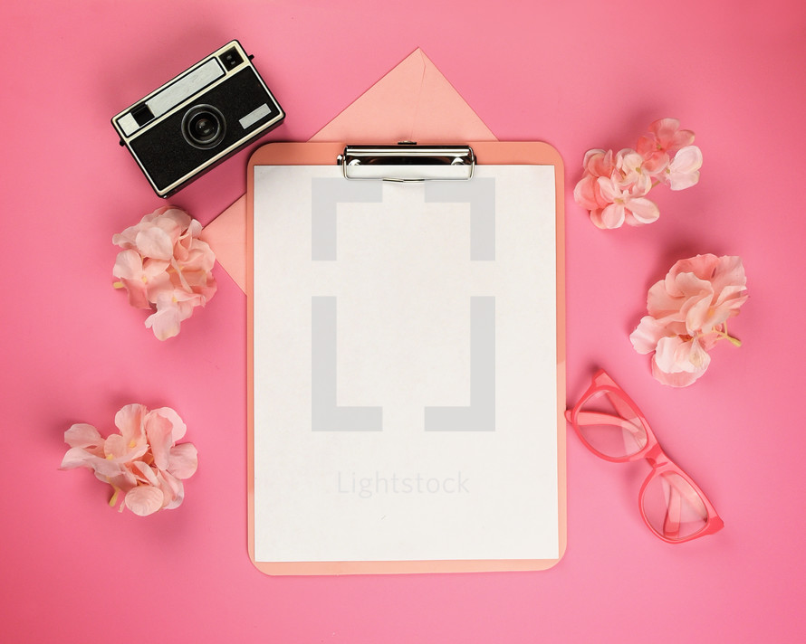 clipboard with white paper and pink items 