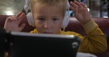 Child in headphones watching cartoon on mobile