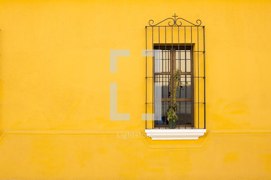bars on a window and a yellow wall 