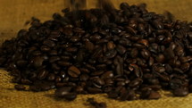 Coffee beans being poured into a pile on burlap
