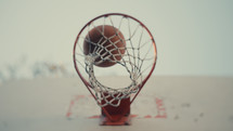 Close up of a basketball being shot on an outdoor basketball court on a sunny day