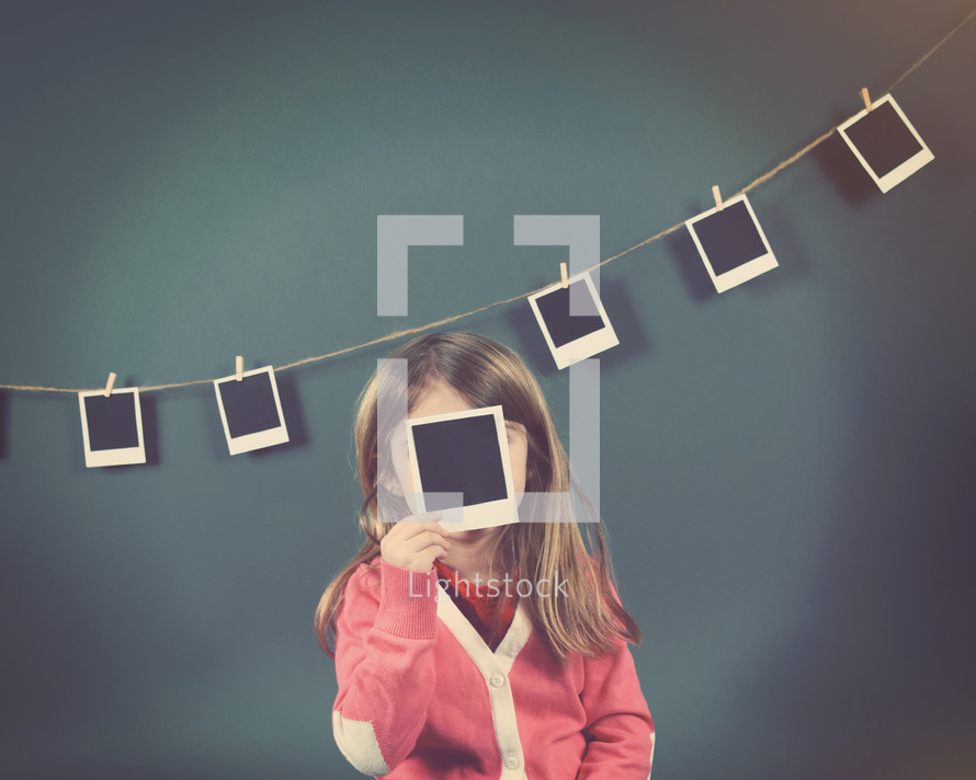 a child holding a polaroid photograph