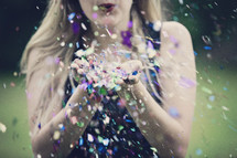 a woman blowing glitter 