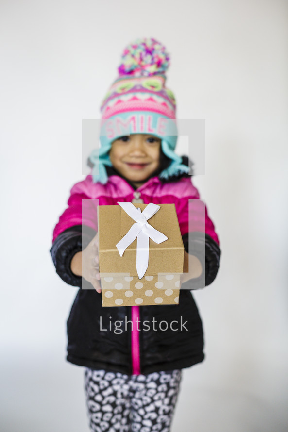 a girl holding a wrapped Christmas gift 