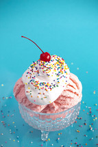 A Strawberry Ice Cream Sundae on a Bright Blue Background with a Cherry on Top
