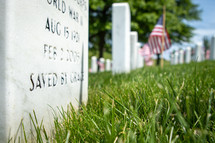 Closeup view of white Christian military gravestone memorial with American flags 