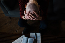 a distressed man praying and reading a Bible for comfort 