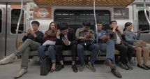 SEOUL, SOUTH KOREA -  Group of male and female commuters sitting in subway train and using smart phones to entertain themselves during the ride