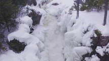 Aerial drone shot captures the breathtaking beauty of a frozen waterfall nestled in a wintry forest landscape