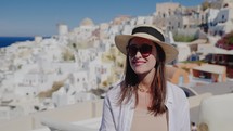 Tourist travel woman in Oia, Santorini, Greece. Happy young woman enjoying view. Beautiful girl visiting the Greek island.
