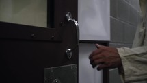 The hand of Jesus Christ opening a prison cell door in cinematic slow motion.