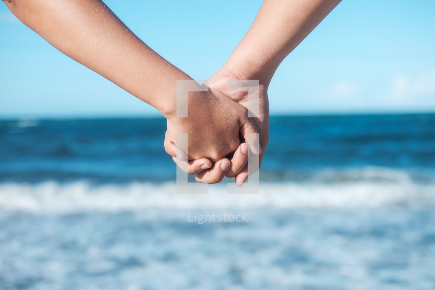 couple holding hands at the beach 